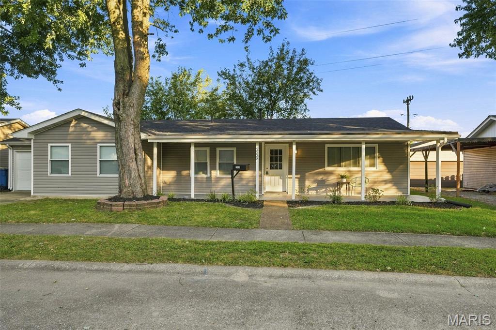 Single-story gray home with a covered front porch and large shade tree.