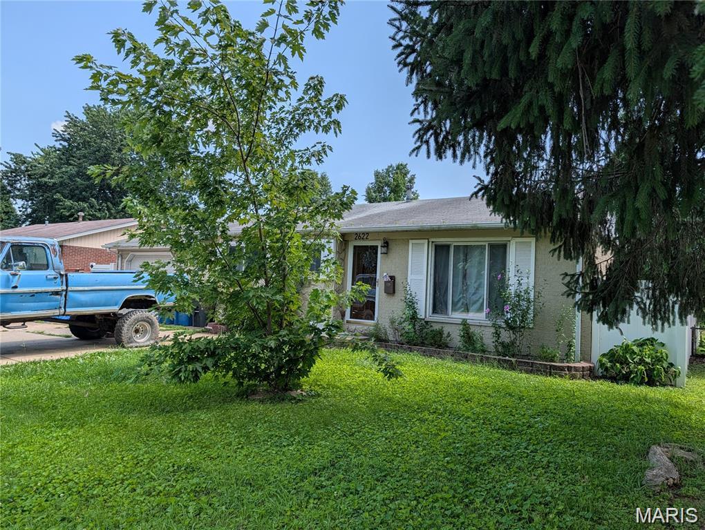 Single-story brick home partly screened by trees, with a blue pickup in the driveway.