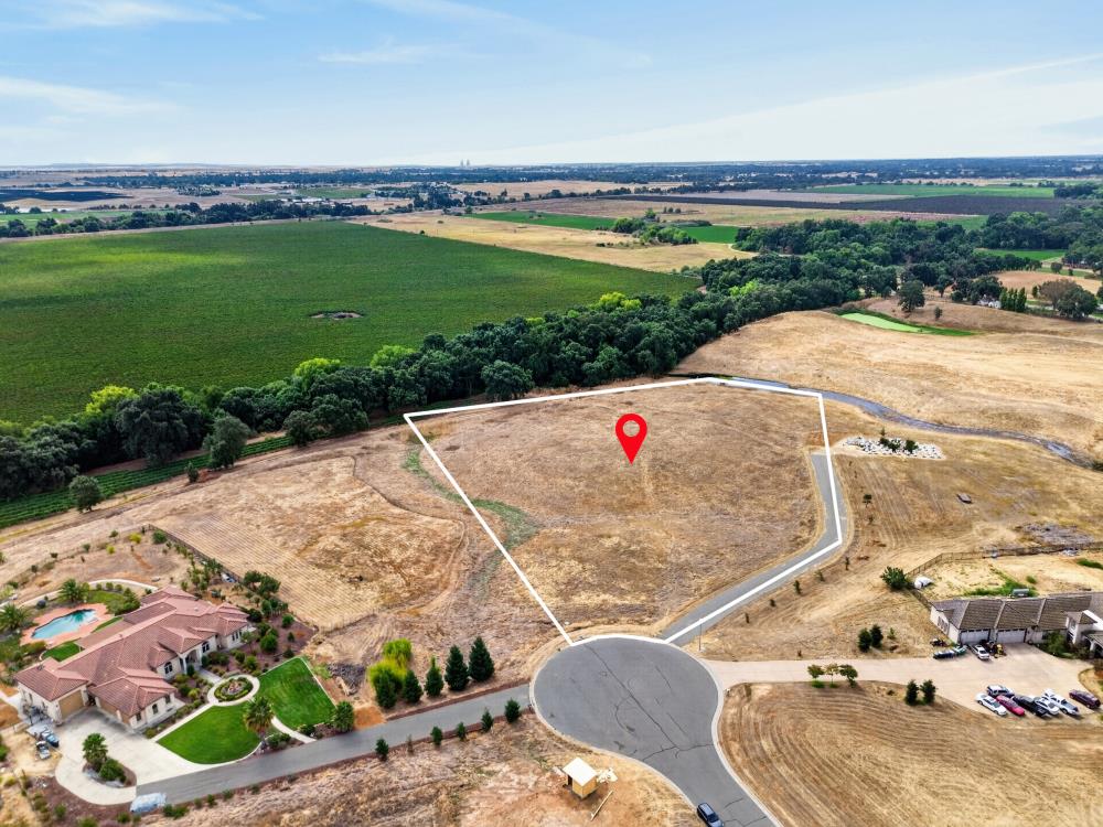 Outlined vacant lot at a cul-de-sac, marked with a red location pin and surrounded by fields.