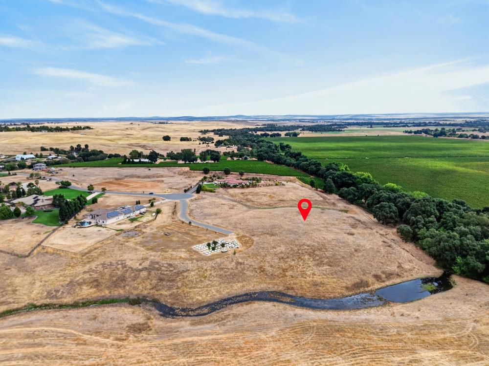 Vacant parcel beside a creek, fields, and a winding access road.