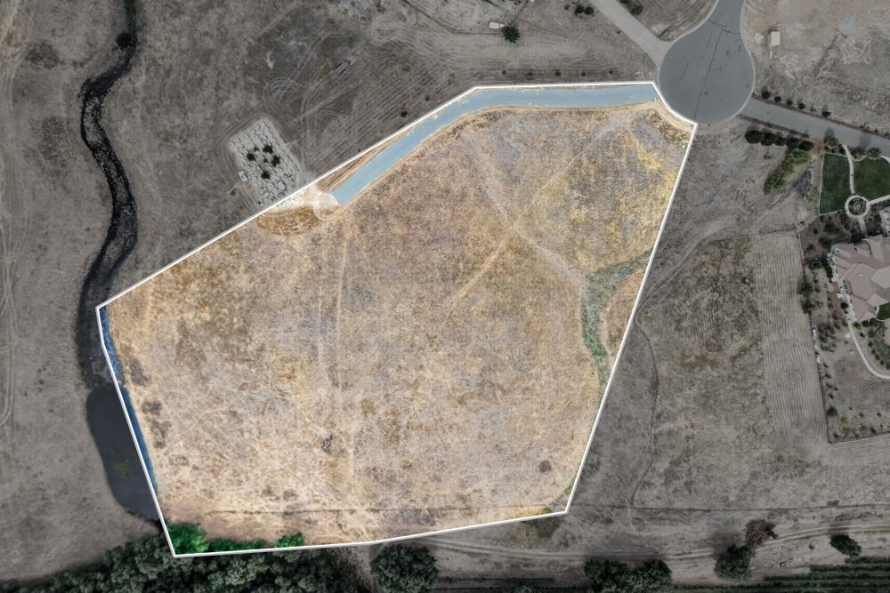 Aerial view of a large vacant lot outlined in white beside a cul-de-sac.