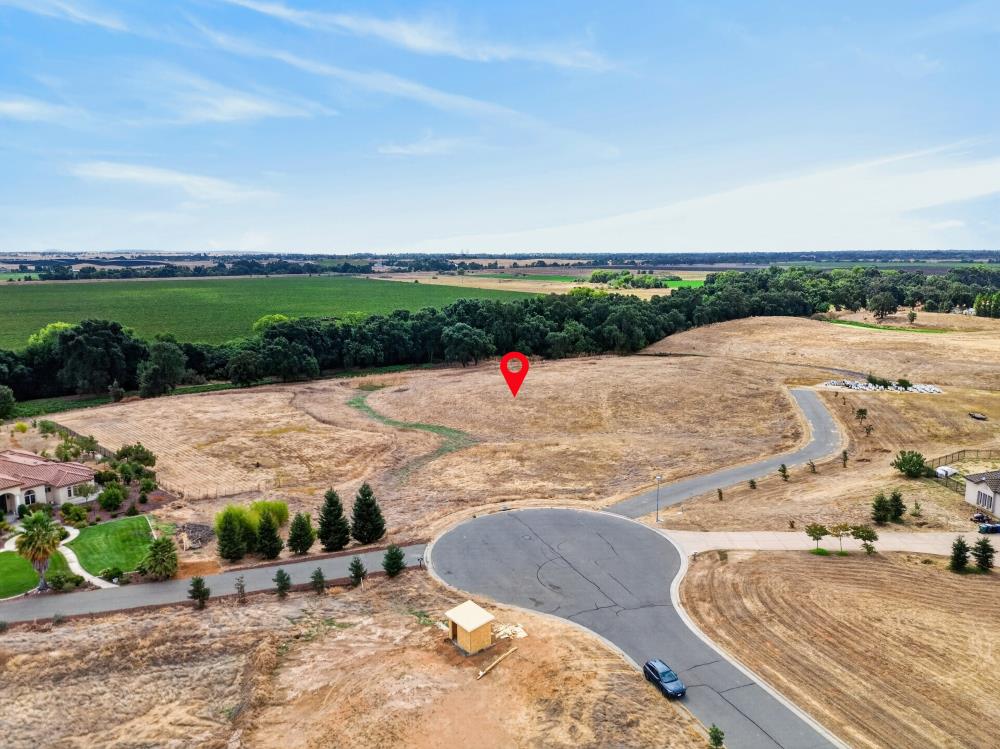 Aerial view of a vacant lot in a cul-de-sac, marked with a red pin and bordered by trees.