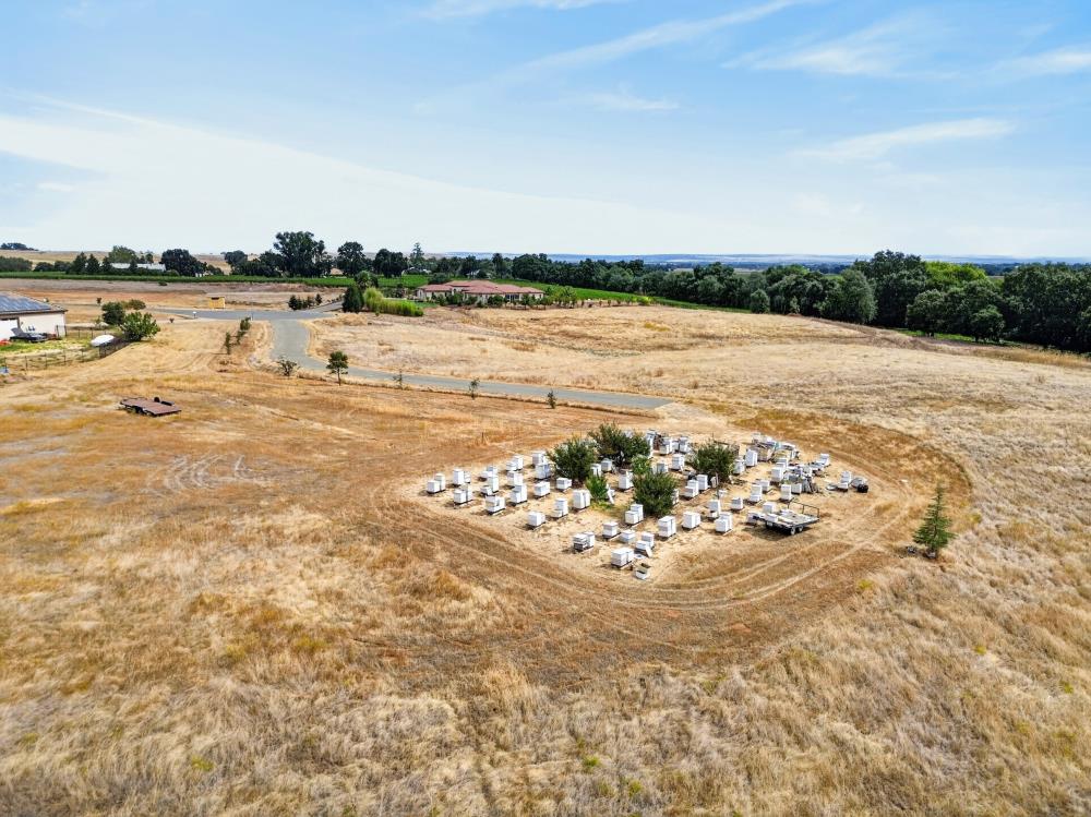 Aerial view of dry open land with a curving road and rows of white box-like structures.
