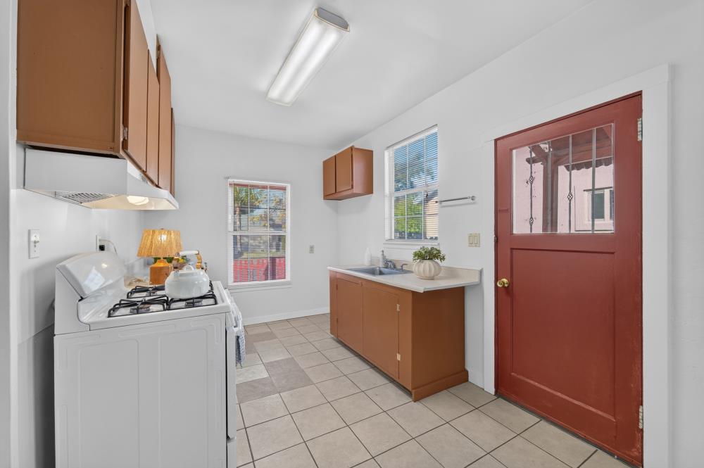 Kitchen with brown cabinets, a gas range, washer, and red door.
