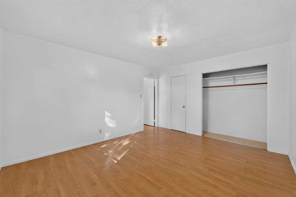 Empty bedroom with light wood floors and a wide open closet.