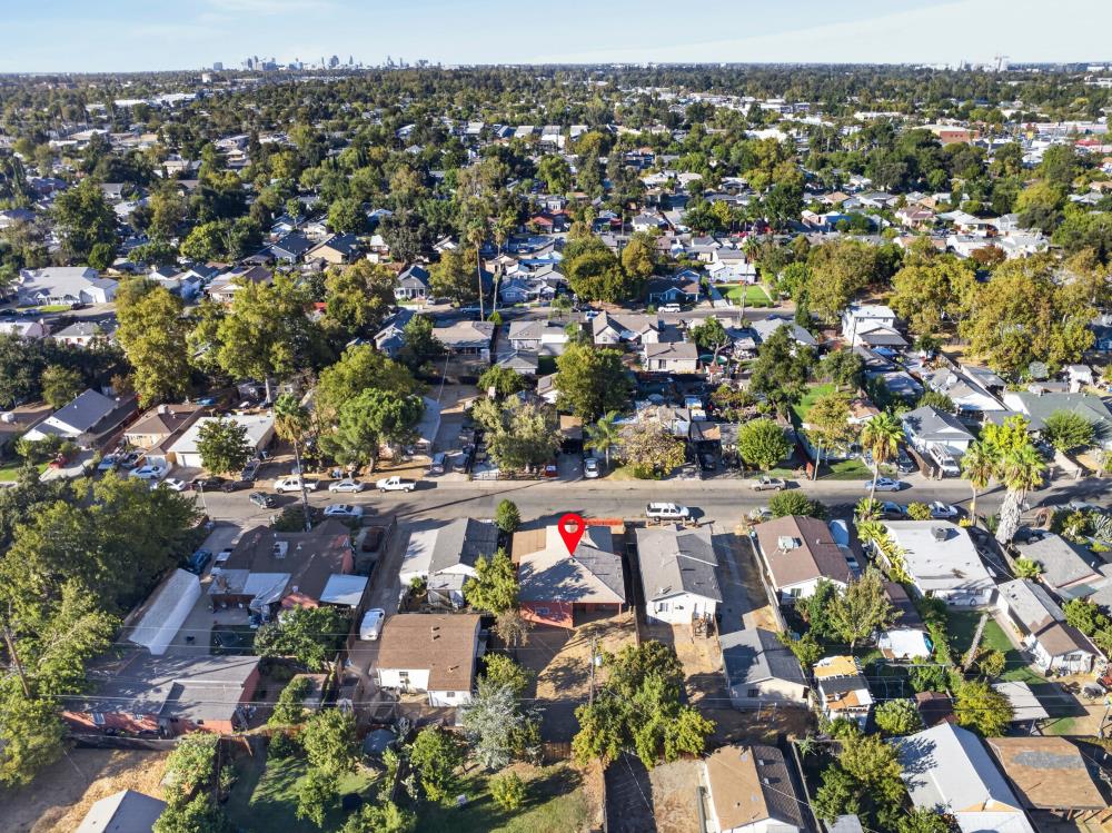 Aerial view of a tree-lined residential neighborhood, with a red pin marking a home near the foreground.