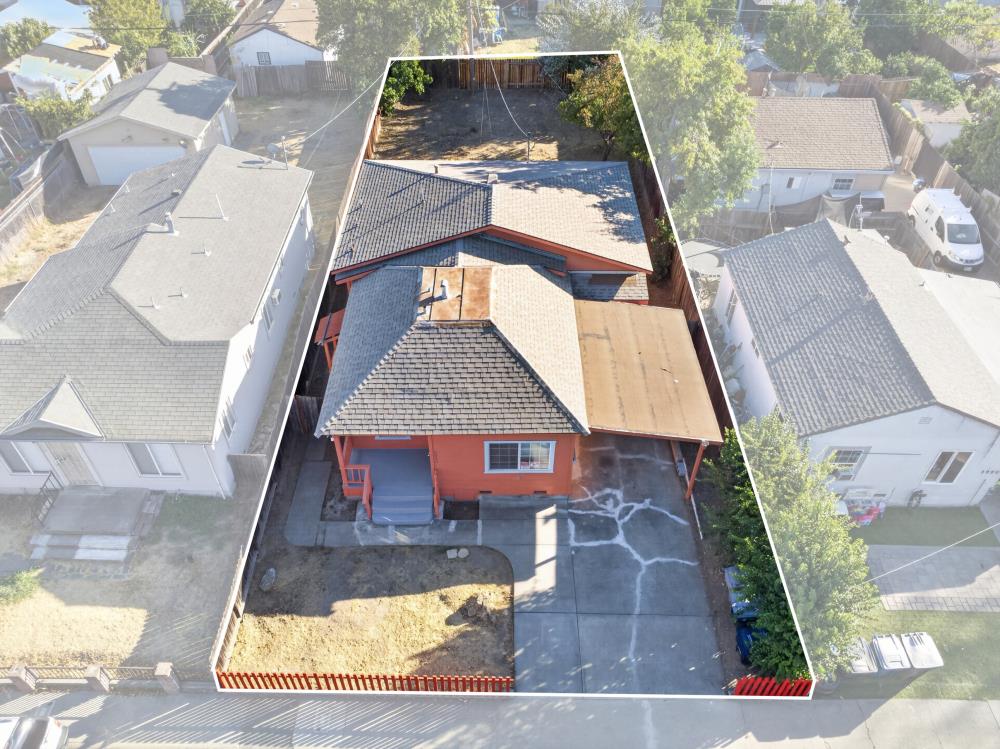 Aerial view of an orange house and its fenced lot, outlined among neighboring homes.