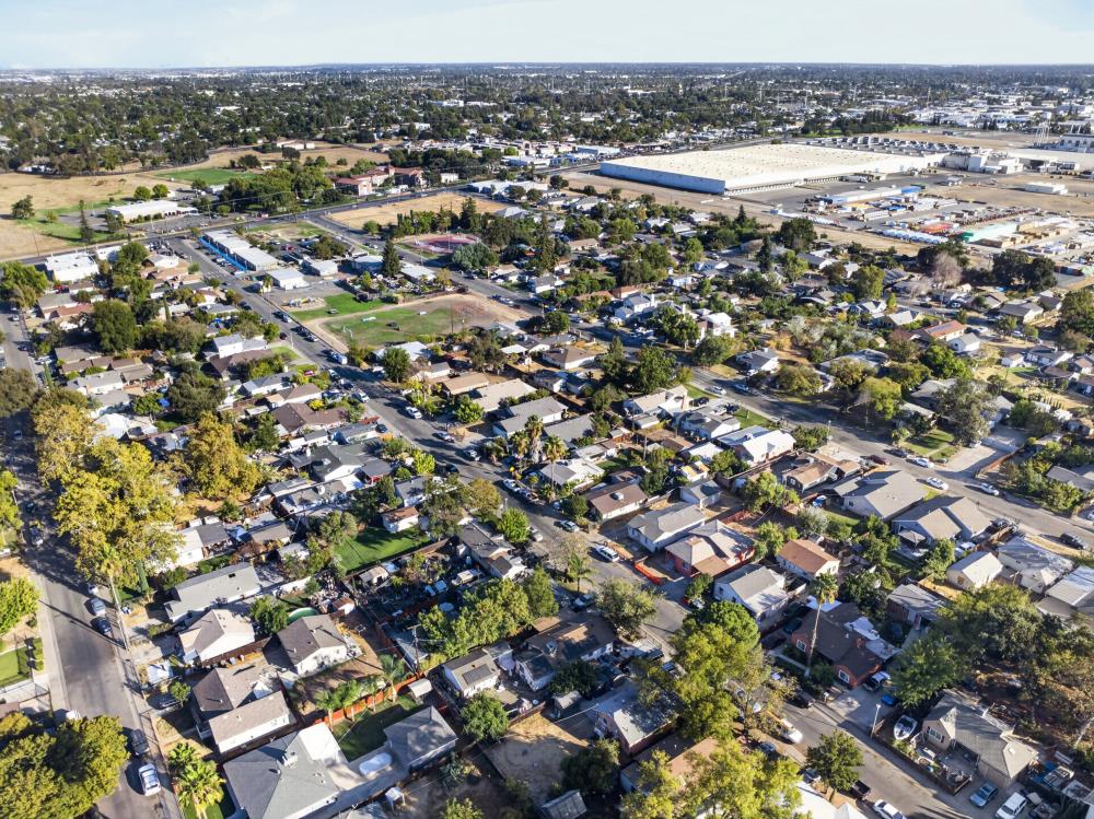 Aerial view of a residential neighborhood with tree-lined streets and large warehouses nearby.