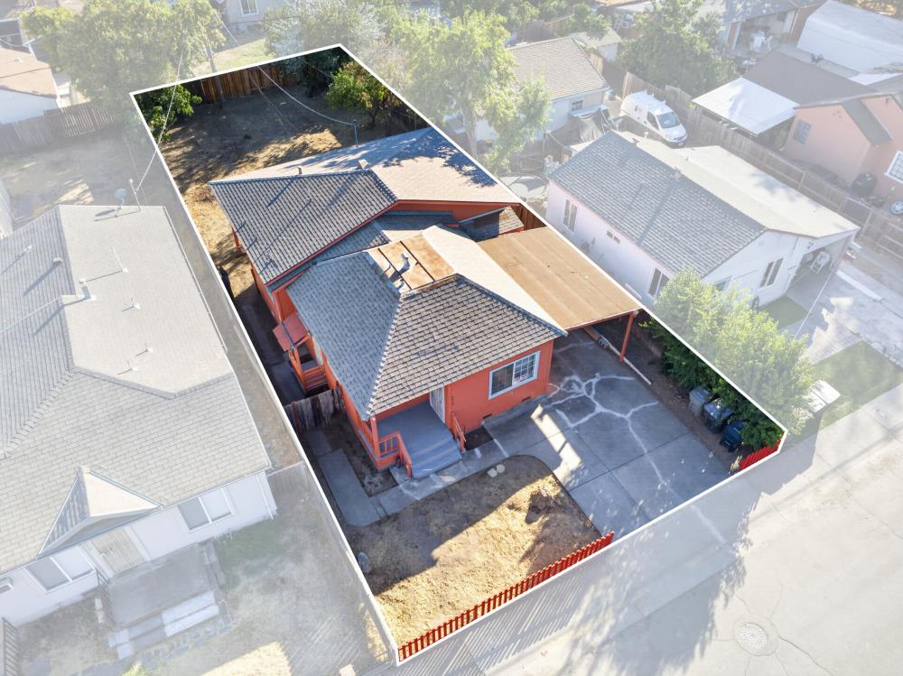 Aerial view of an orange house with a fenced yard and concrete driveway.