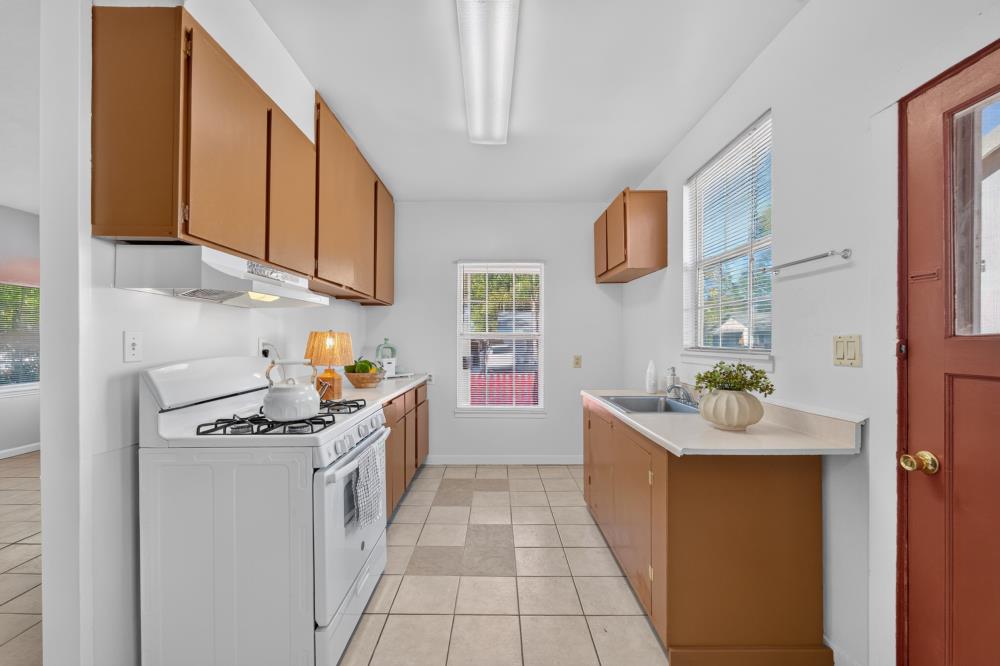 Kitchen with brown cabinets, a white gas range, and a sink beneath a window.