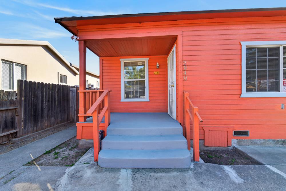 Red-orange house with a covered porch, blue-gray steps, and address 2940 beside the door.