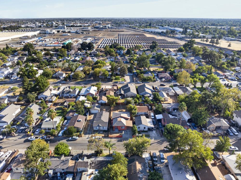 Aerial view of a Sacramento neighborhood with tree-lined streets and a large solar panel installation.