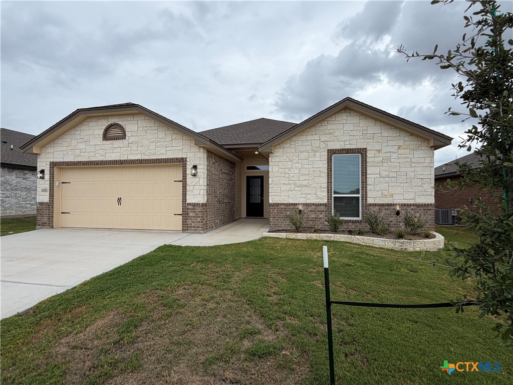Single-story stone-and-brick house with a two-car garage and broad front lawn.
