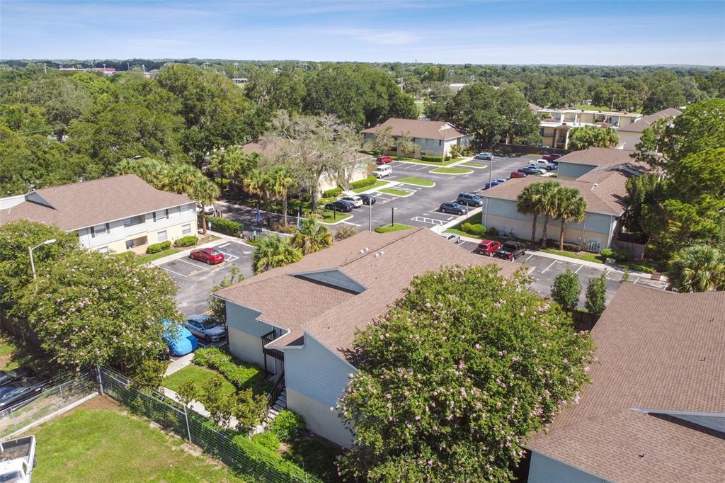 Aerial view of a townhouse community with parking lots, mature trees, and landscaped grounds.