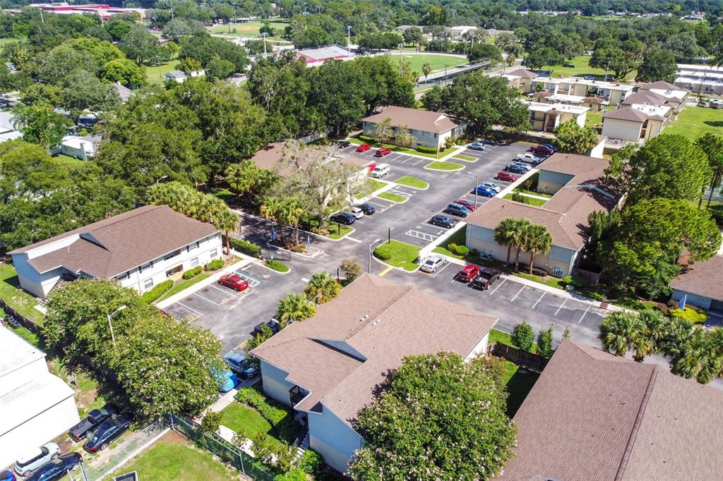 Aerial view of a condominium complex with parking lots, low-rise buildings, and mature trees.
