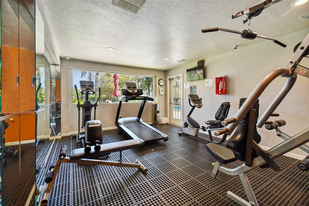Fitness room with treadmills, exercise bikes, weight machines, and a large window.