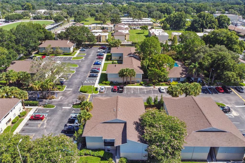 Aerial view of a condominium community with tree-lined buildings, parking lots, and a small swimming pool.