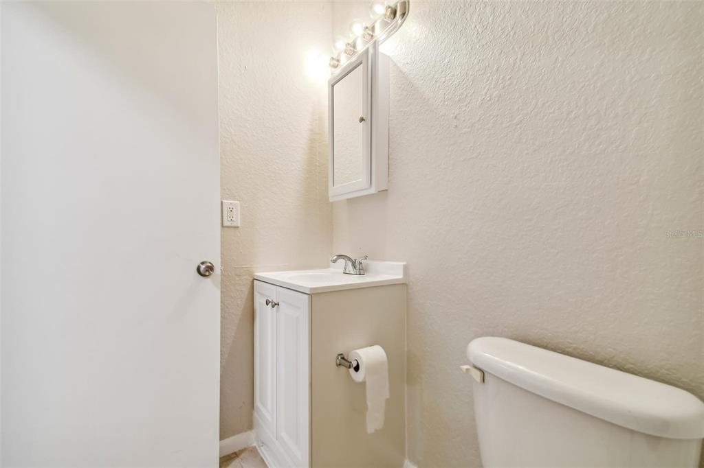 Bathroom vanity and sink beside a toilet, with a wall mirror above.