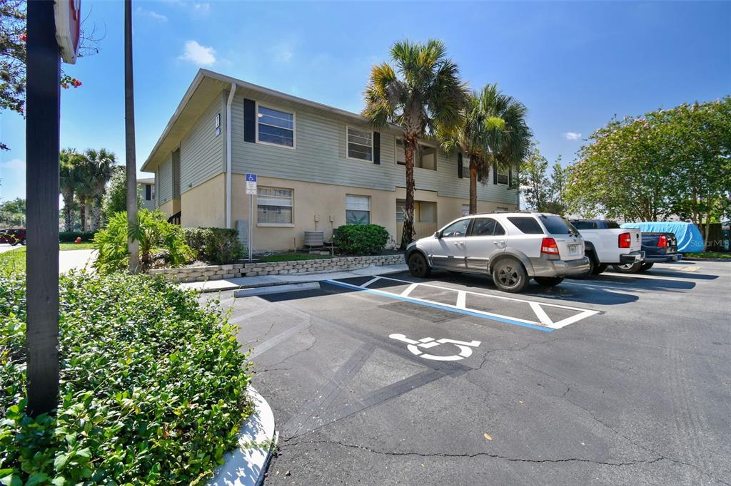 Two-story condominium exterior with palm trees and an accessible parking space in front.