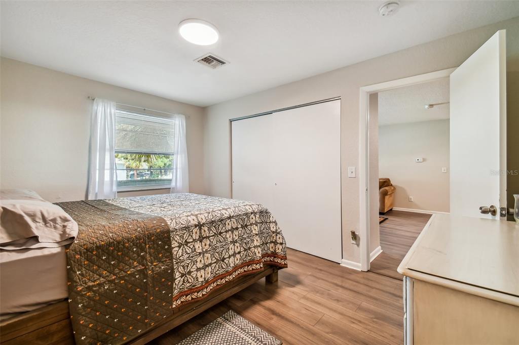 Furnished bedroom with a patterned bedspread, sliding closet doors, and an open doorway to the adjoining room.
