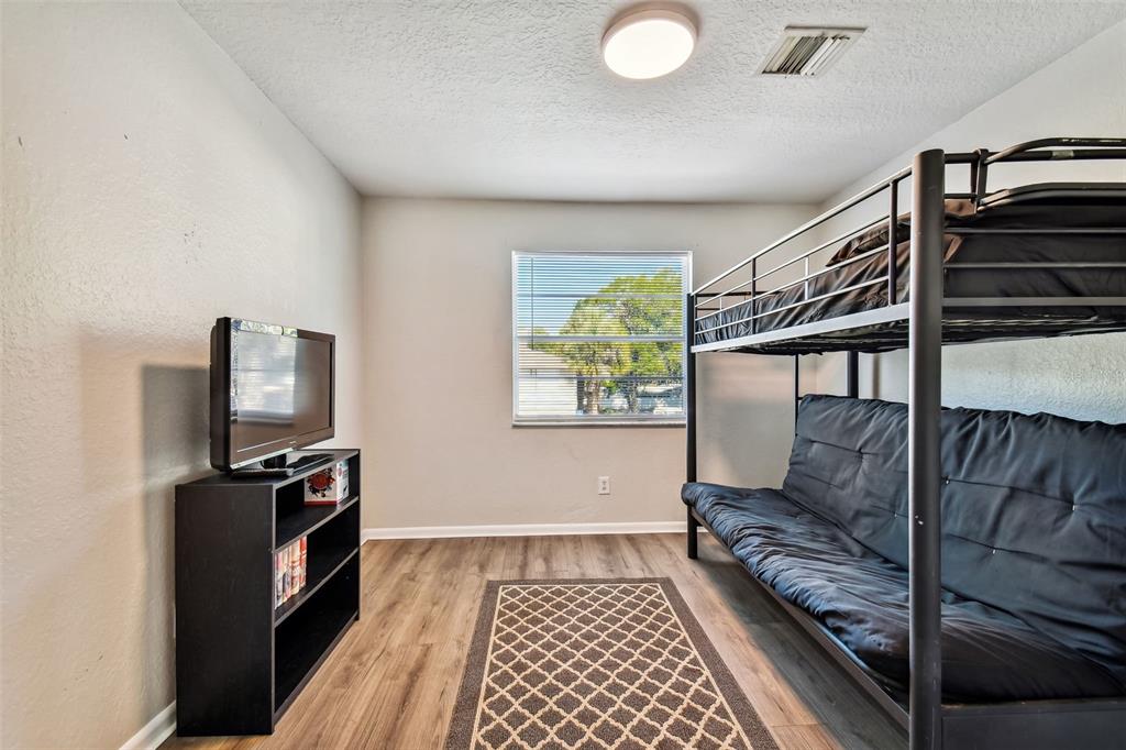 Bedroom with a black metal bunk bed, lower futon, and television on a media cabinet.