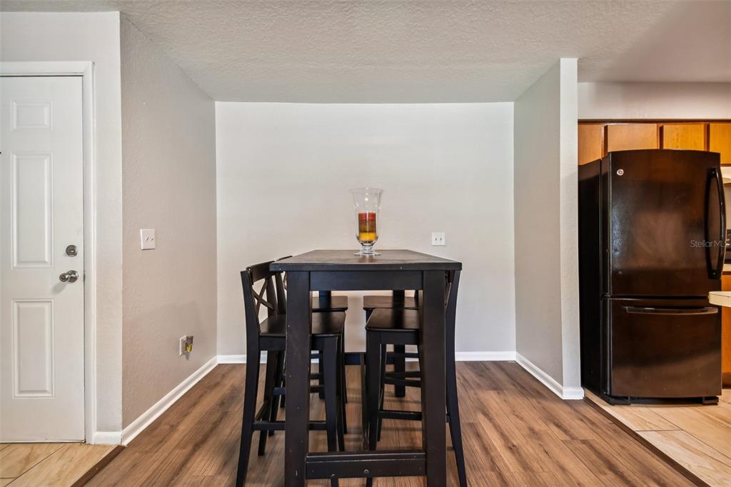 Dining area with a dark high-top table and stools beside the adjoining kitchen.