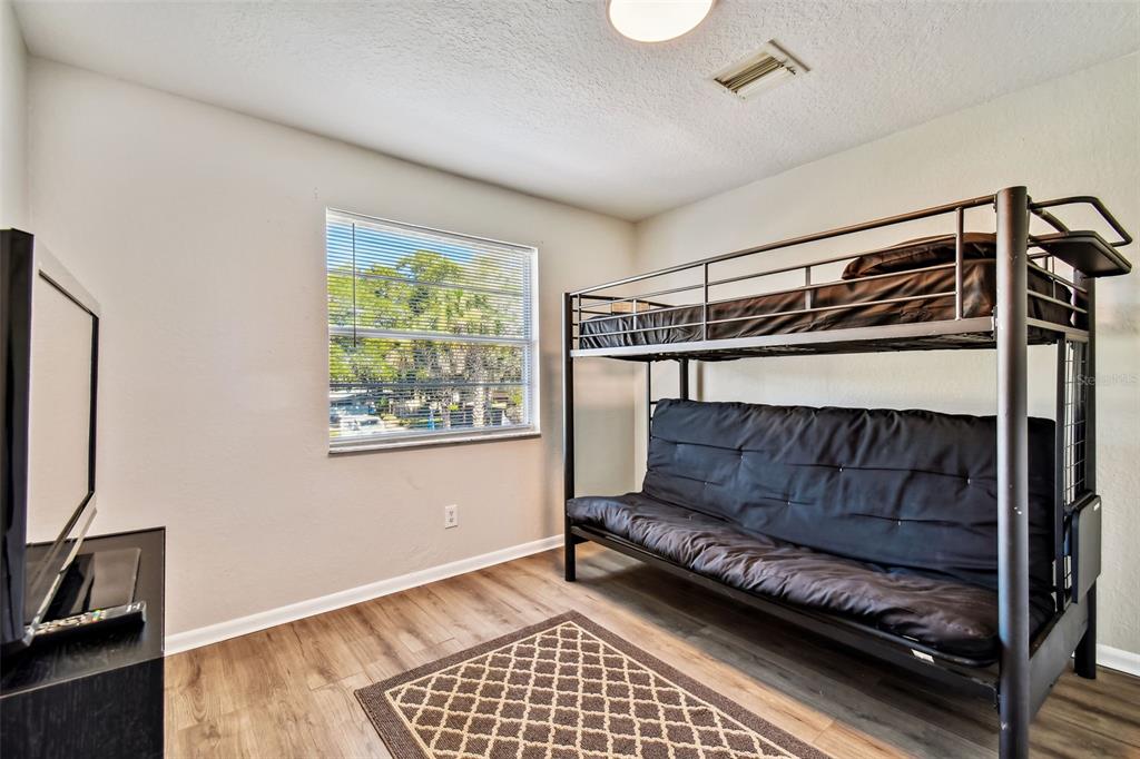 Bedroom with a black metal bunk bed, lower futon, and patterned rug.