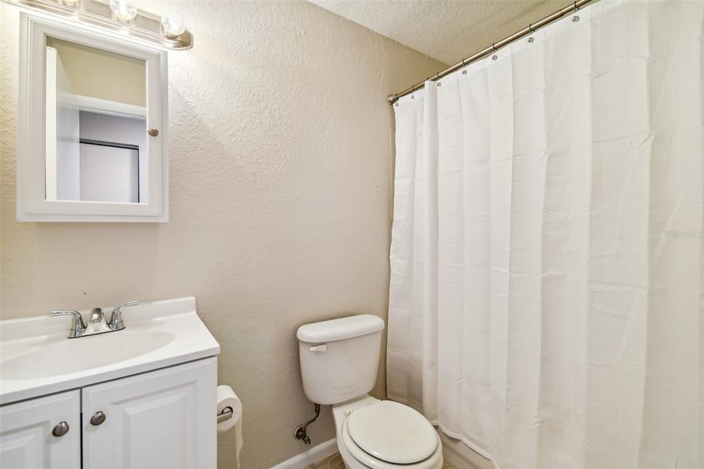 Bathroom with a white vanity, toilet, and curtained bathtub or shower.