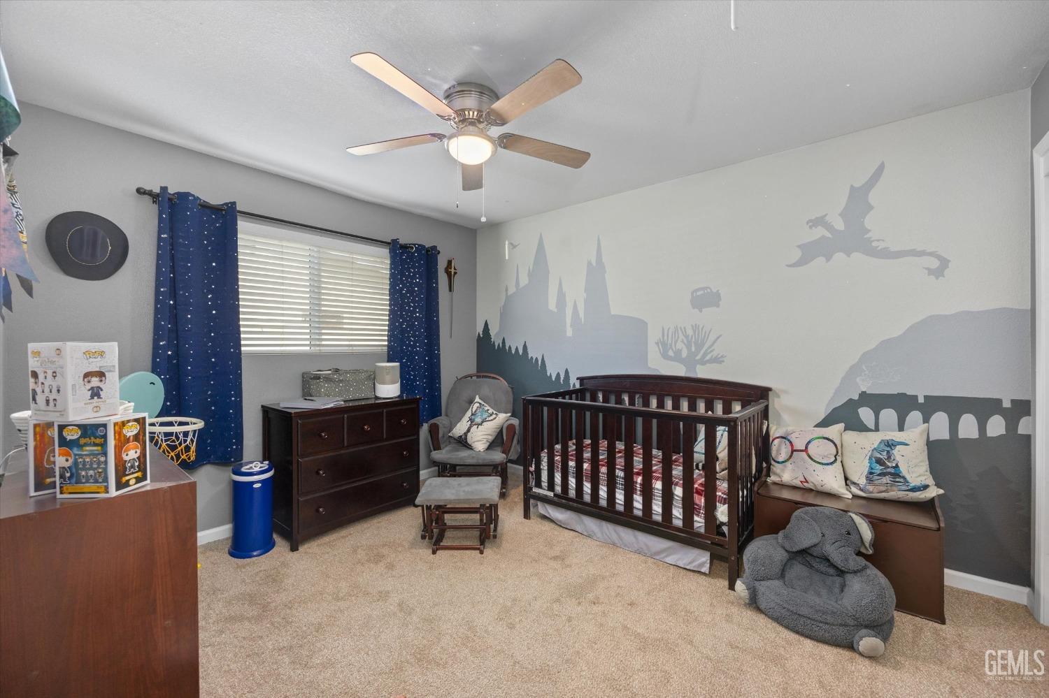 Nursery bedroom with a dark wood crib, star-patterned curtains, and a large fantasy-themed wall mural.
