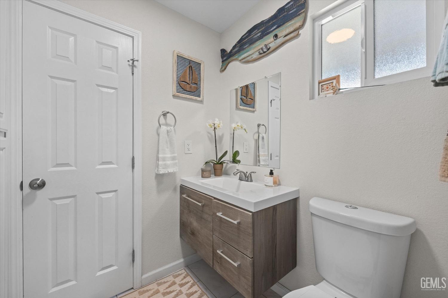 Bathroom with a wood-tone vanity, white sink, and nautical wall decorations.