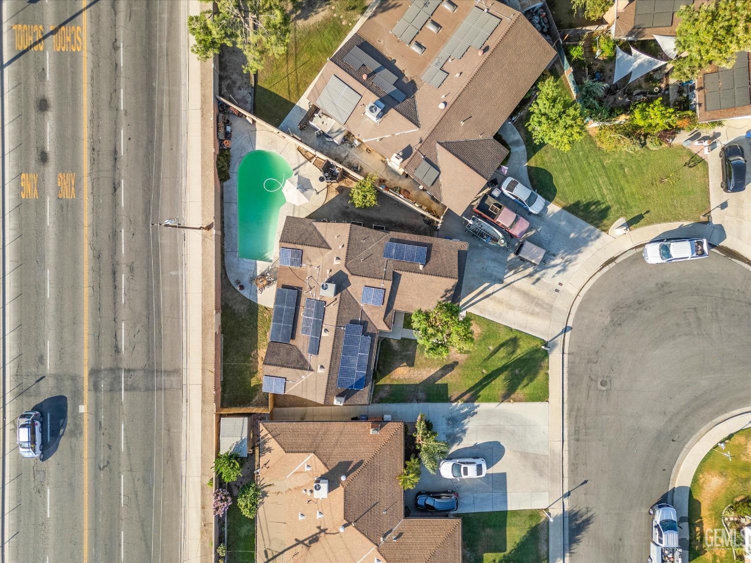 Aerial view of a home with a curved pool and solar panels on the roof.