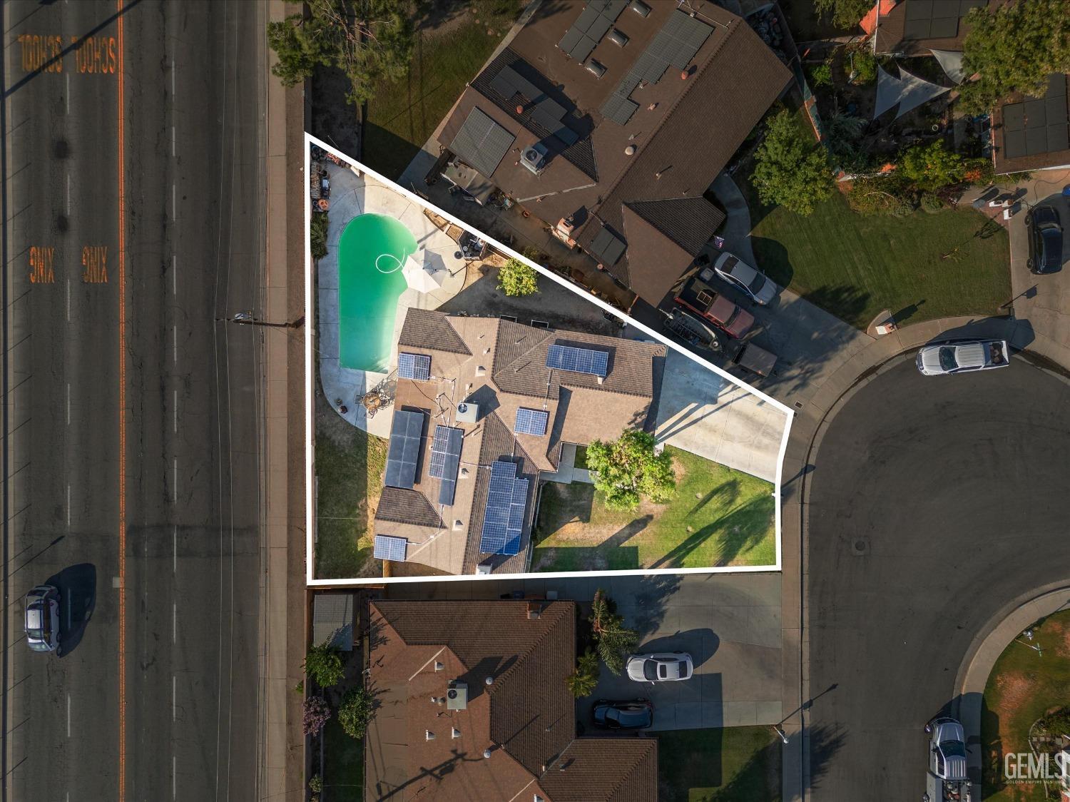 Aerial view of a home with a swimming pool and solar panels on a marked corner lot.