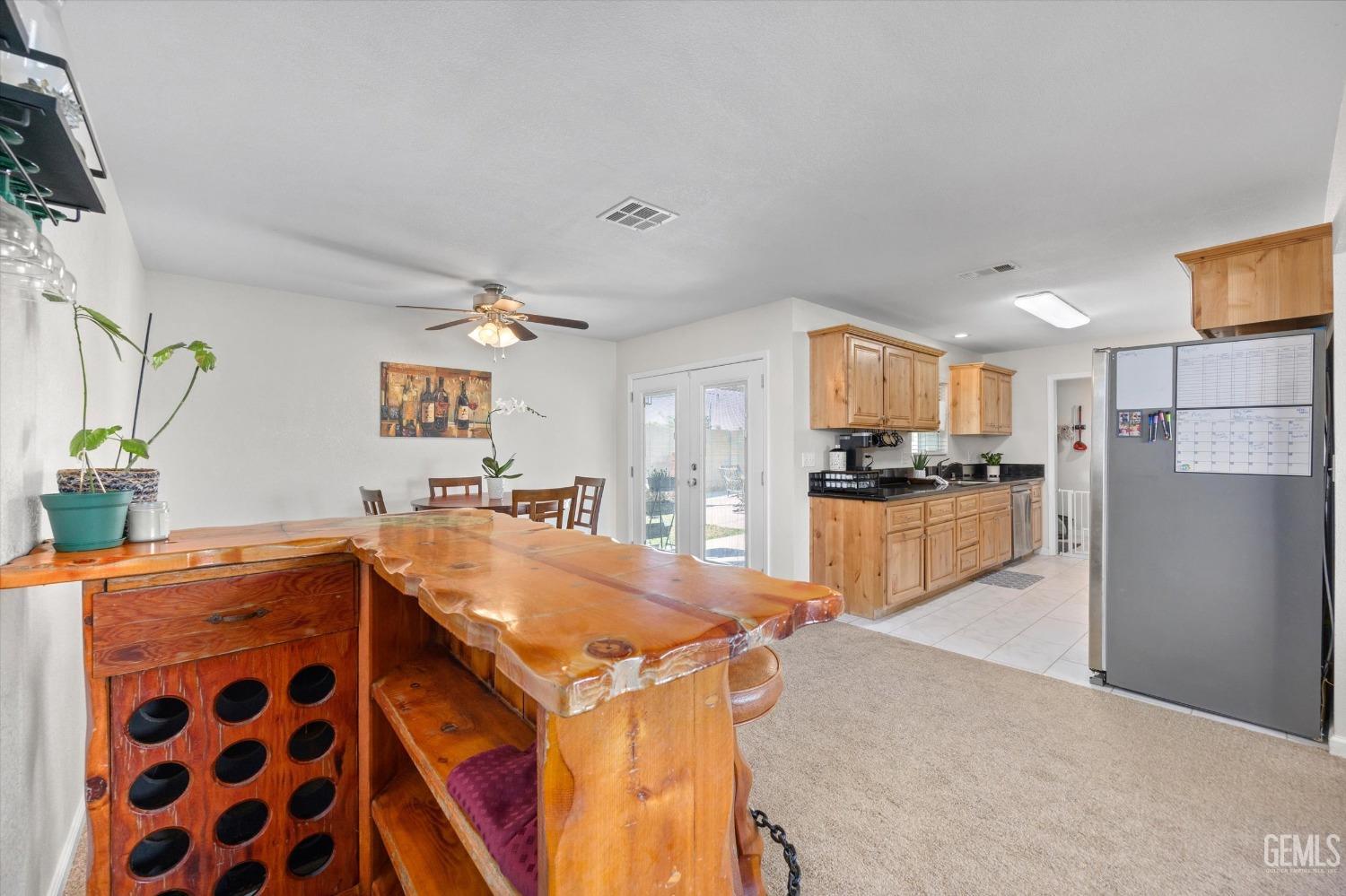 Open kitchen and dining area with honey-colored cabinets and a live-edge wooden bar with wine storage.