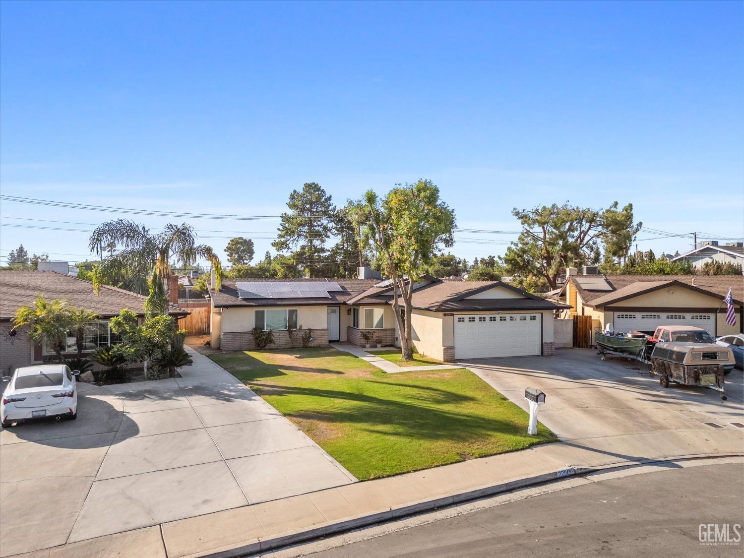 Single-story home with solar panels, a two-car garage, and a broad driveway.
