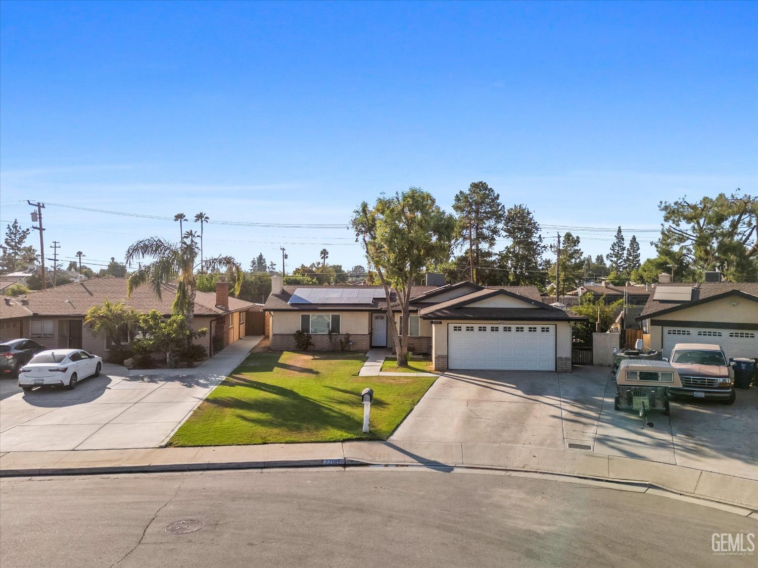 Single-story home with rooftop solar panels, a two-car garage, and a front lawn.