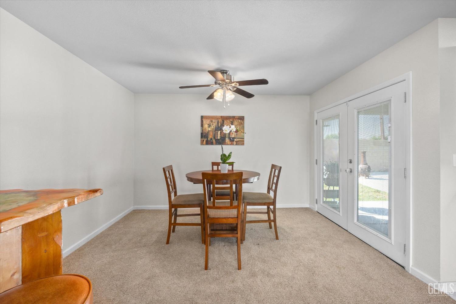 Dining room with a round wooden table, ceiling fan, and glass patio doors.
