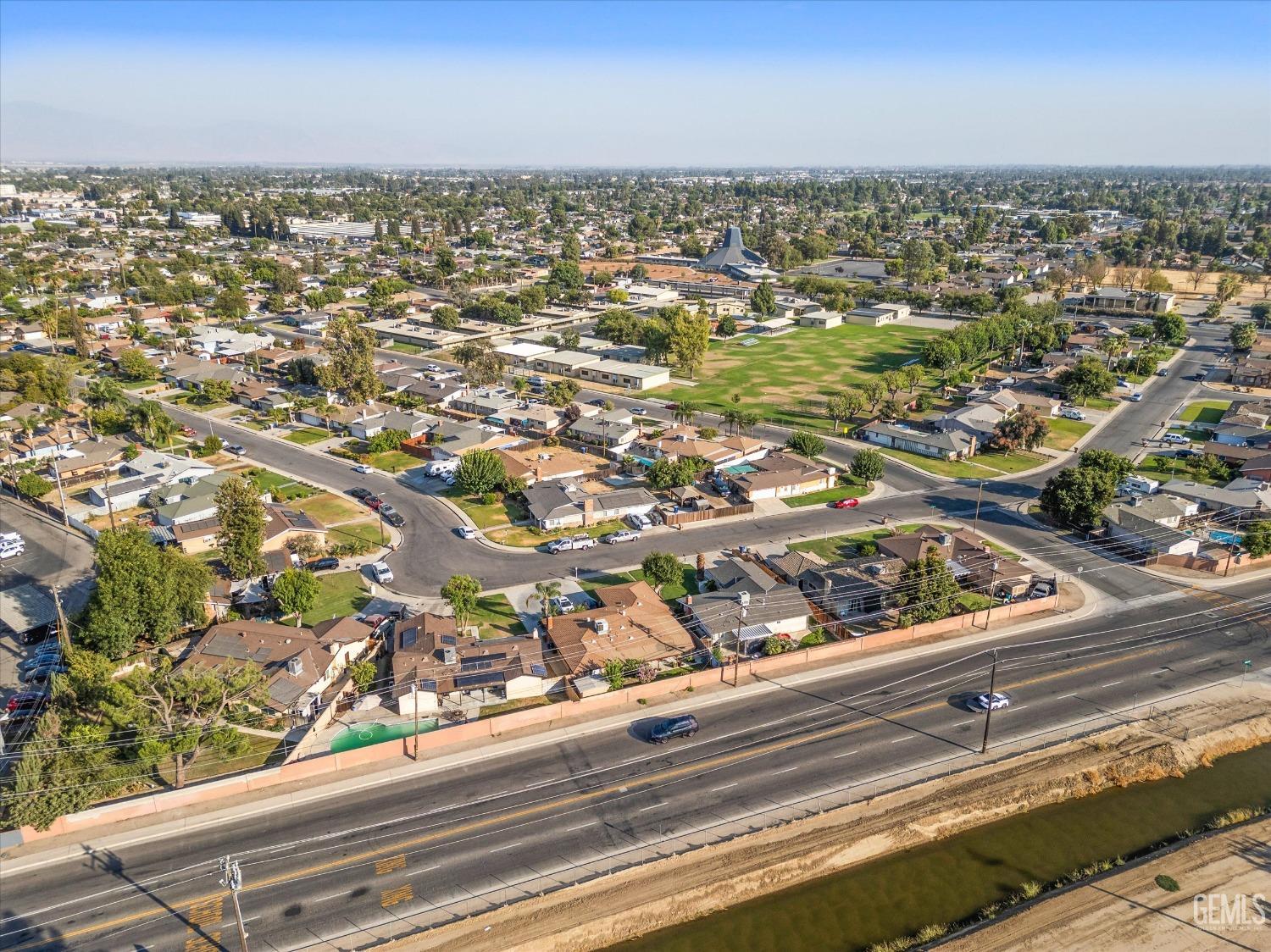 Aerial view of the neighborhood, with a park, residential streets, and a canal beside a divided road.