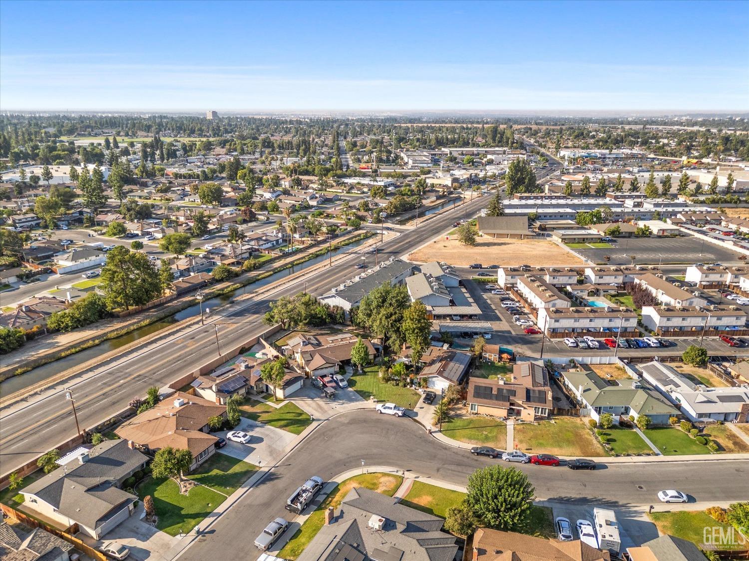 Aerial neighborhood view with homes, a canal, and a major road.