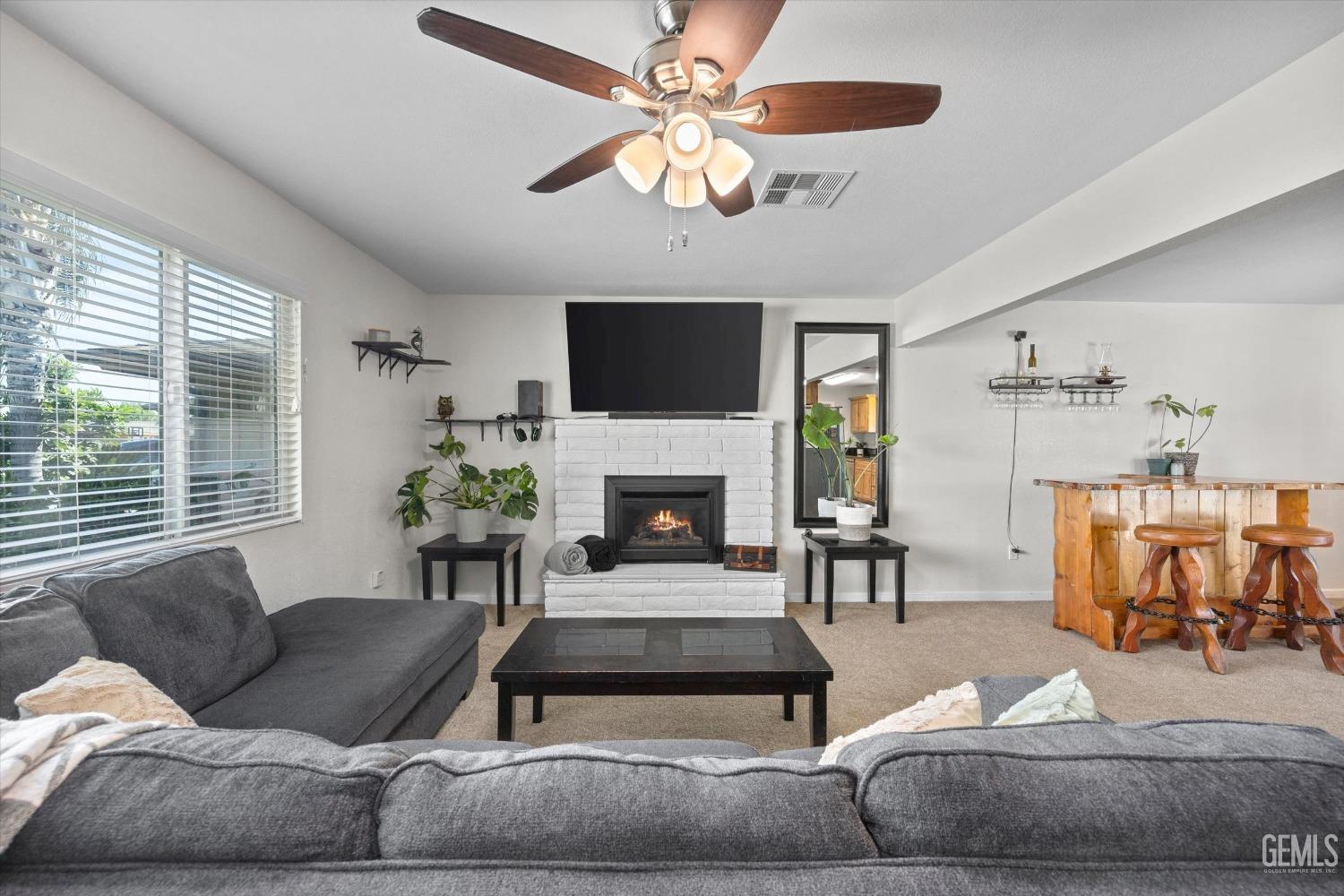 Living room with a white brick fireplace, gray sectional, and wooden bar with stools.