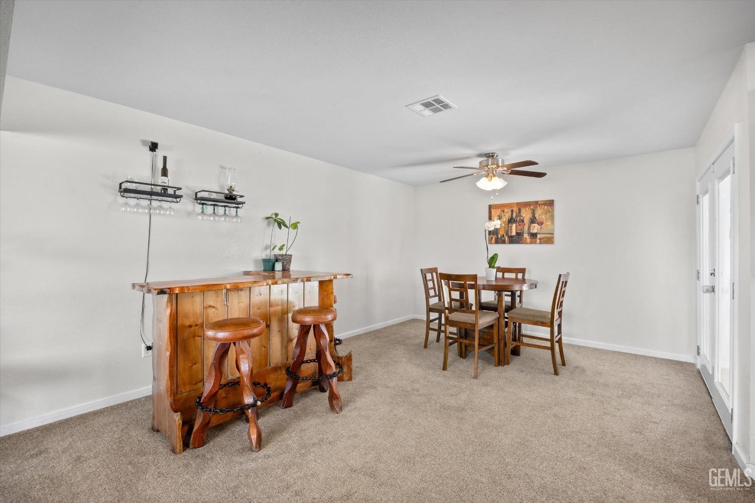 Dining area with a rustic wooden bar and stools beside a round table and chairs.