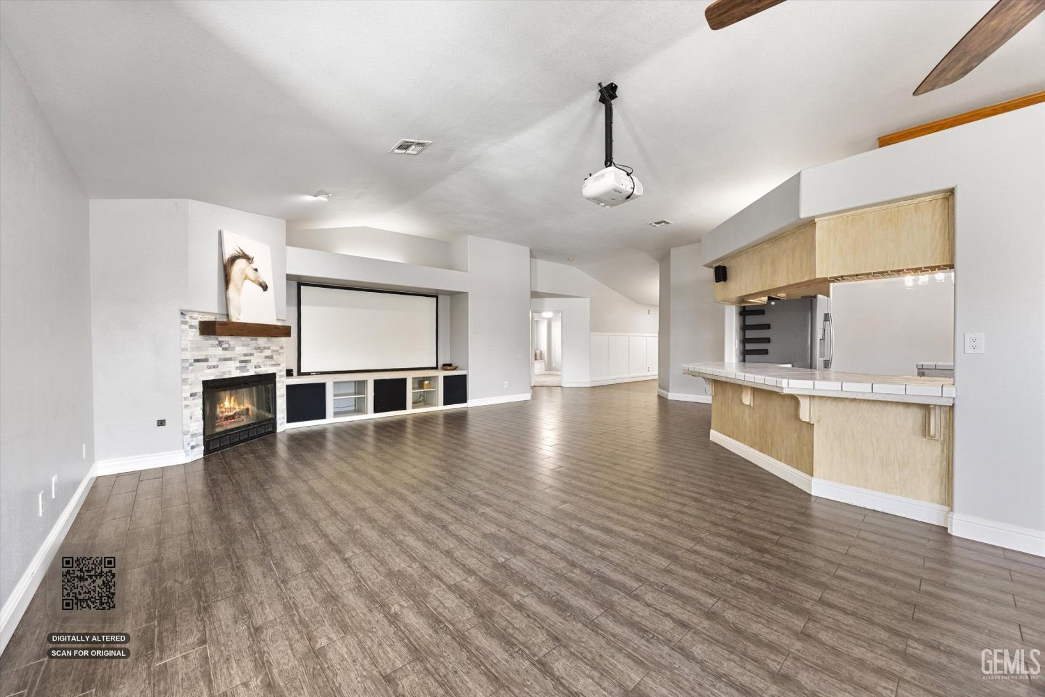 Living room with a stone fireplace, projector screen, and kitchen bar.