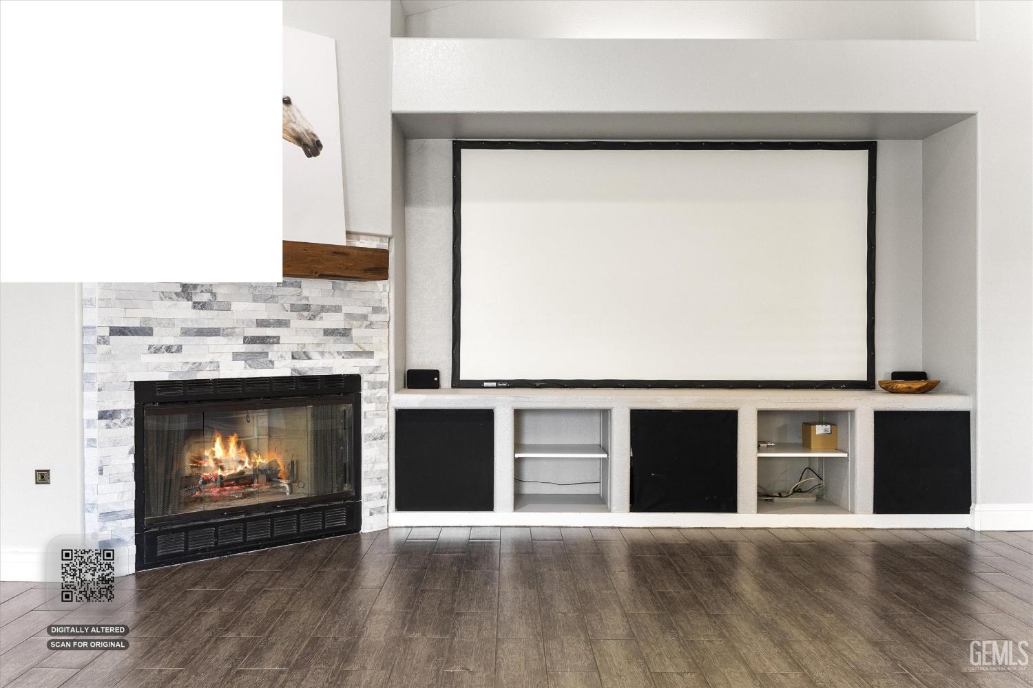 Living room with a large projection screen above built-in shelving and a lit stone fireplace.