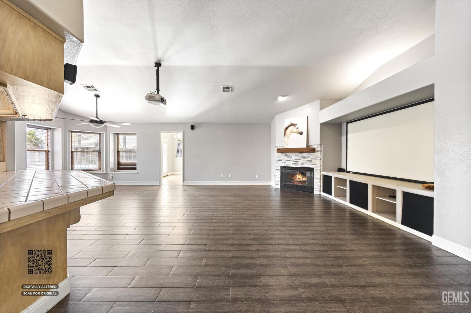 Unfurnished living room with a fireplace, large projection screen, and dark tile flooring.
