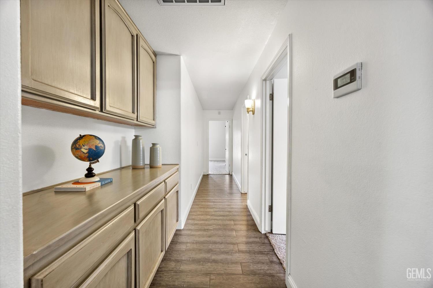 Hallway with built-in light wood cabinets, wood-look tile flooring, and a globe on the counter.