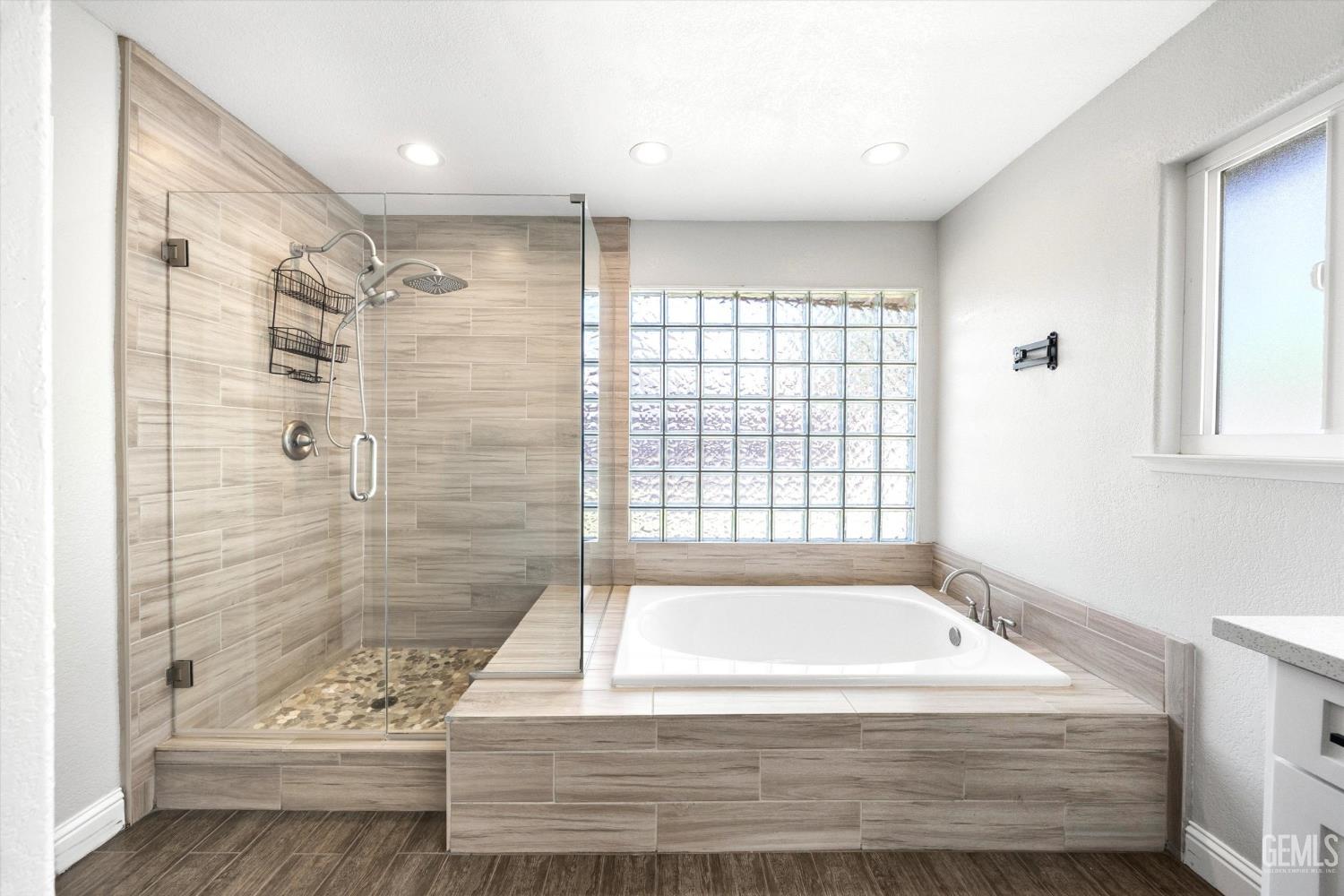 Bathroom with a glass-enclosed tiled shower, built-in soaking tub, and glass-block window.