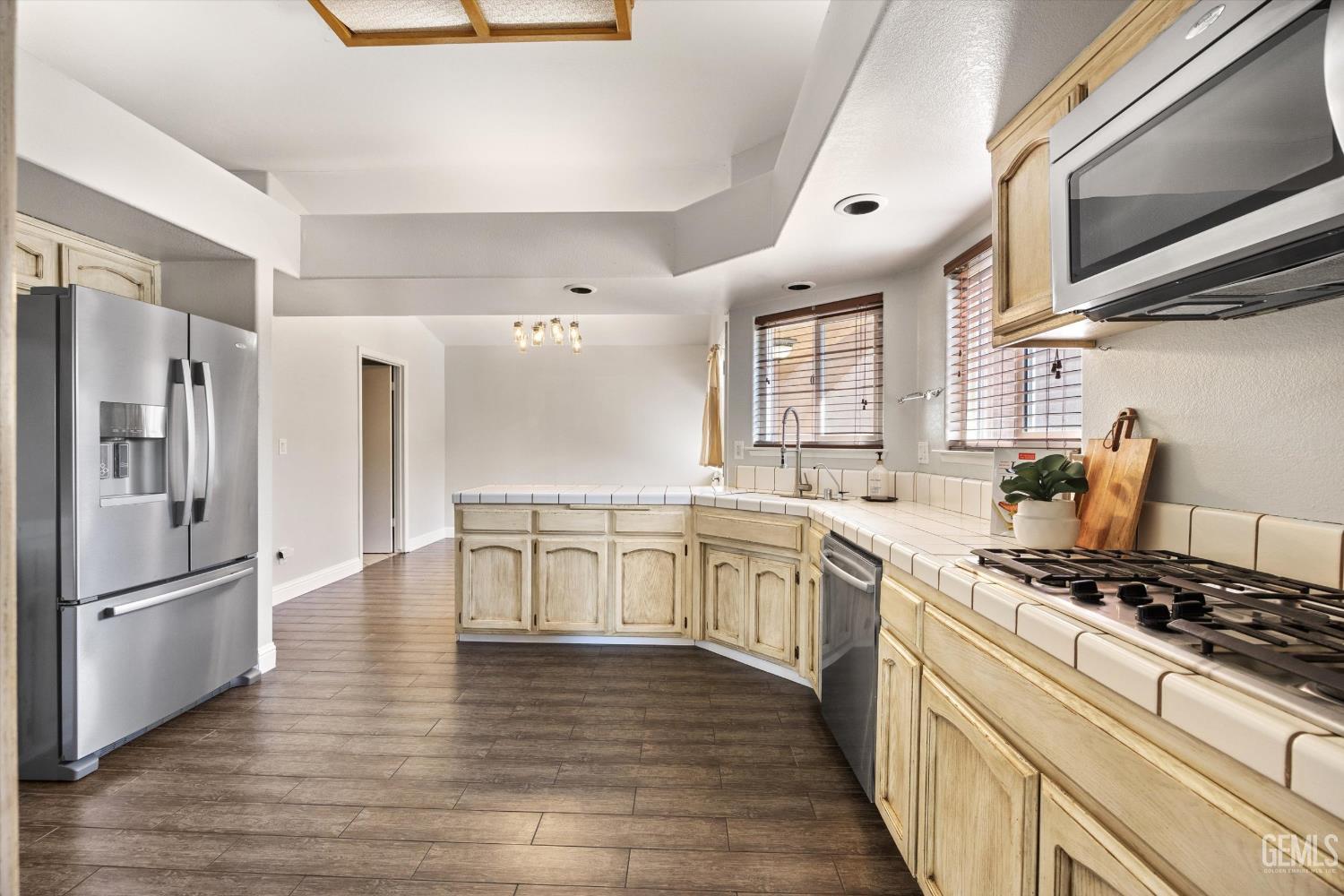 Kitchen with cream cabinets, tile counters, stainless appliances, and a gas range.