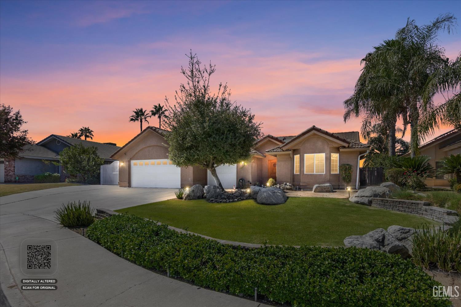 Single-story stucco home with a two-car garage and landscaped yard at dusk.
