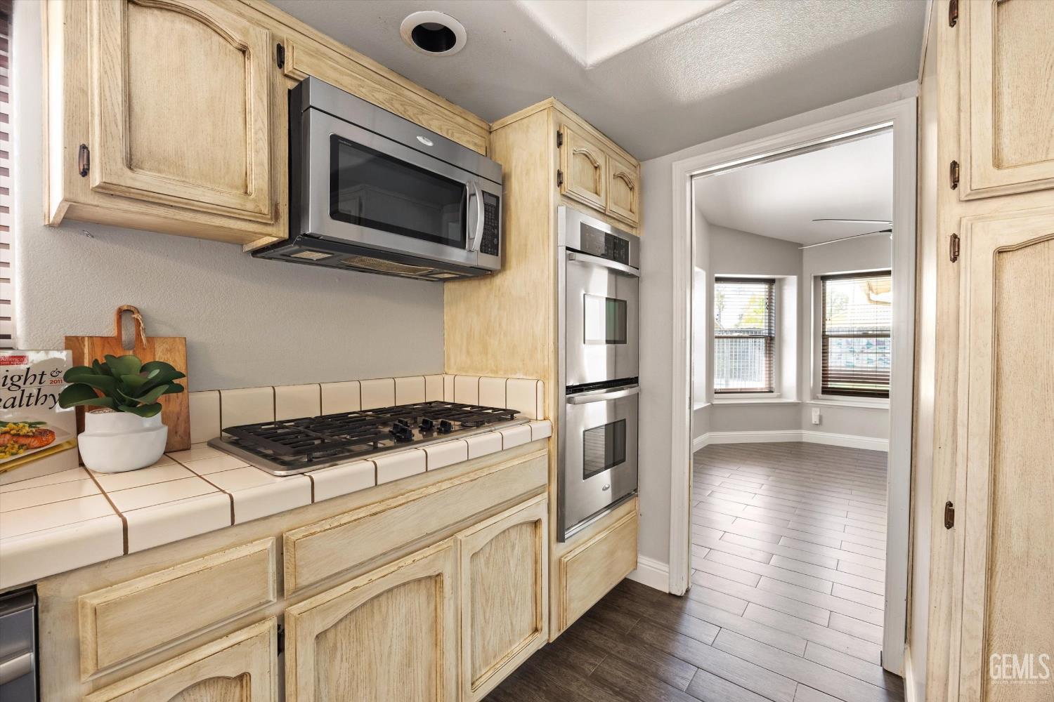 Kitchen with light wood cabinets, tiled counters, a gas cooktop, and stainless steel appliances.