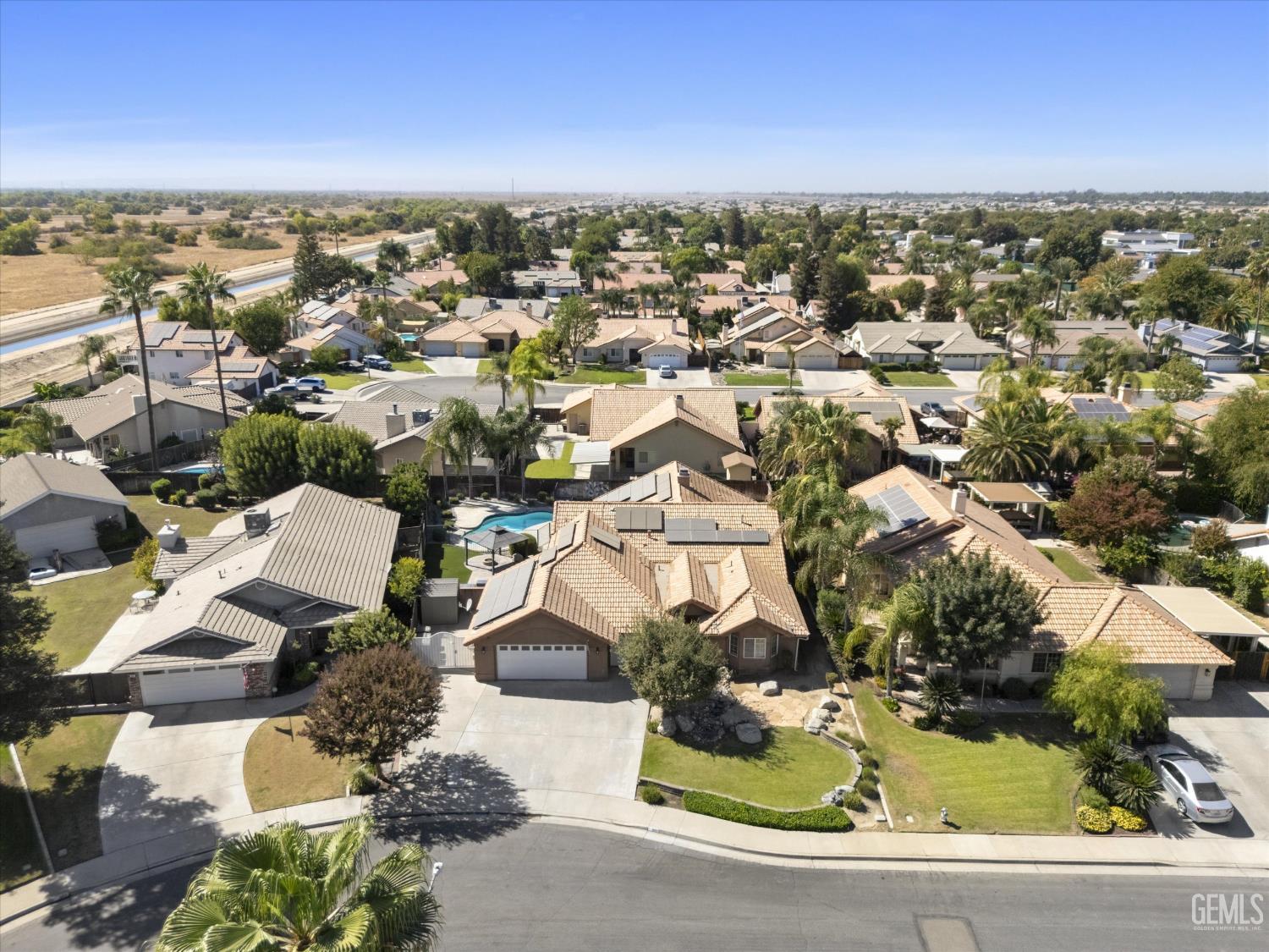 Aerial view of the home and surrounding neighborhood, with tile roofs, backyard pools, and a curved street.
