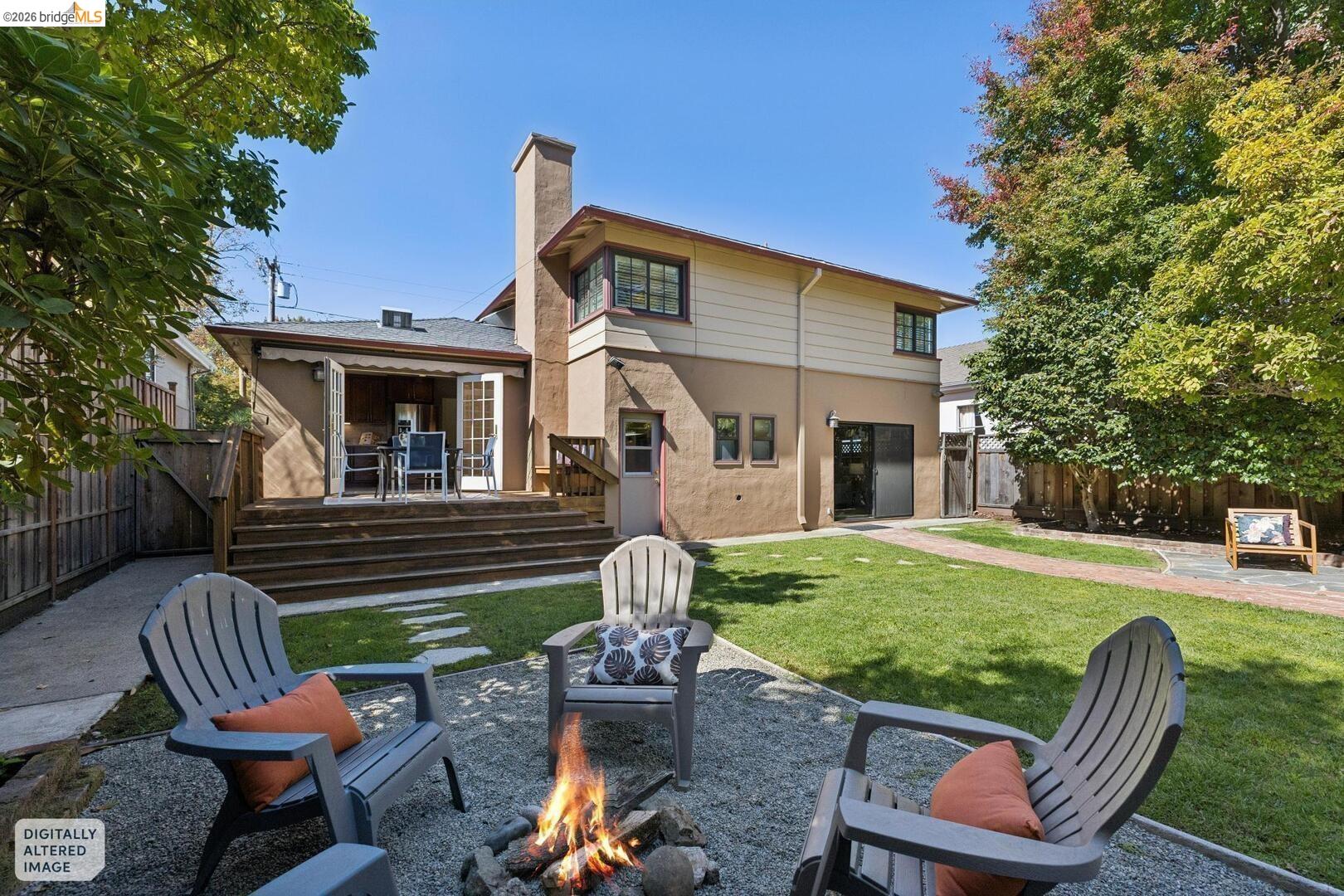 Home’s backyard with a raised deck, lawn, and patio seating around a fire pit.